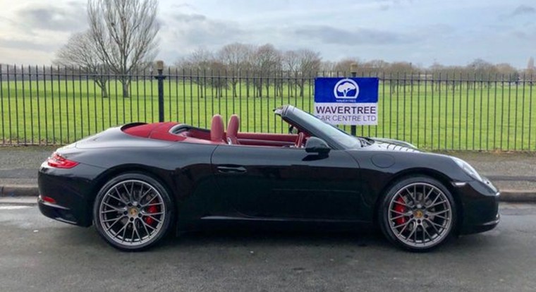 Black Porsche 911 convertible with red leather interior.
