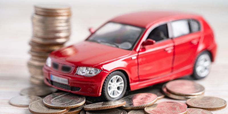 A vibrant red car resting on piles of coins, representing the car finance process