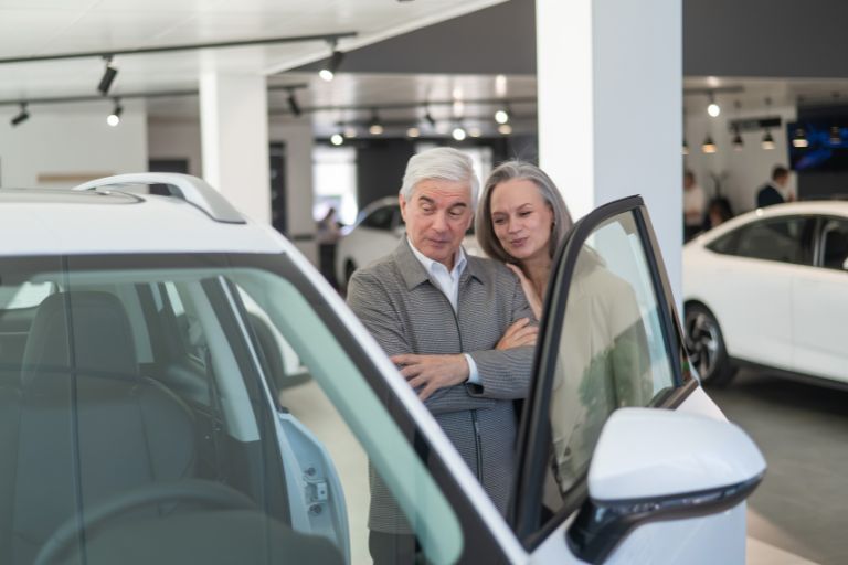 An old couple viewing cars in a car dealership
