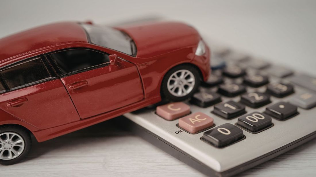 A Red Toy Car Sitting On a Calculator
