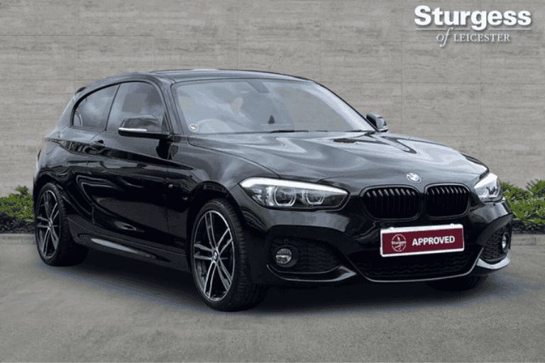 Black BMW 1 Series hatchback parked outside Sturgess of Leicester dealership showroom.