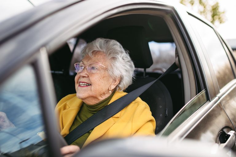 an old woman test driving a car with a big smile on her face