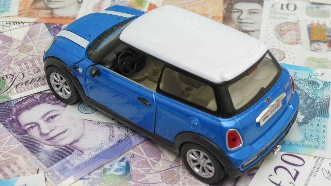 A Blue Toy MINI Cooper on a Pile of Money