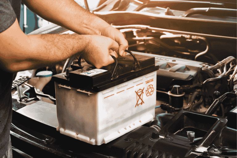a man lowering a car battery under the bonnet