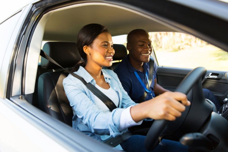 A young girl driving with her driving instructor