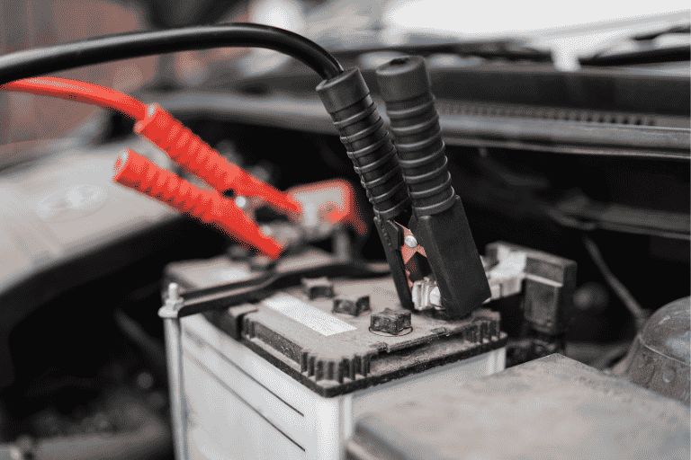 a car battery with two jump leads attached.