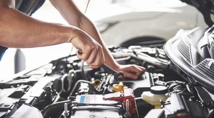 A Man Holding a Tool Inside an Open Bonnet 