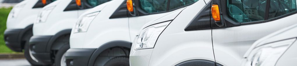 Four white vans lined up diagonally