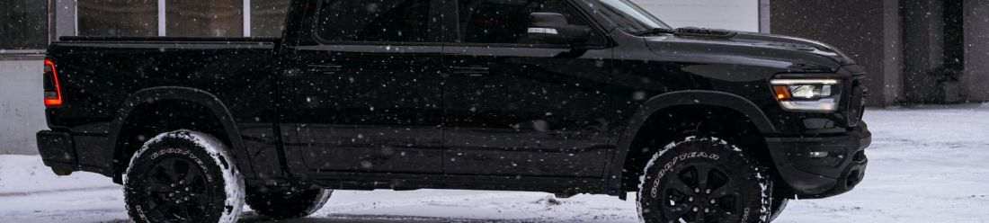 A black pick up parked on a snowy landscape, surrounded by a serene winter scene.
