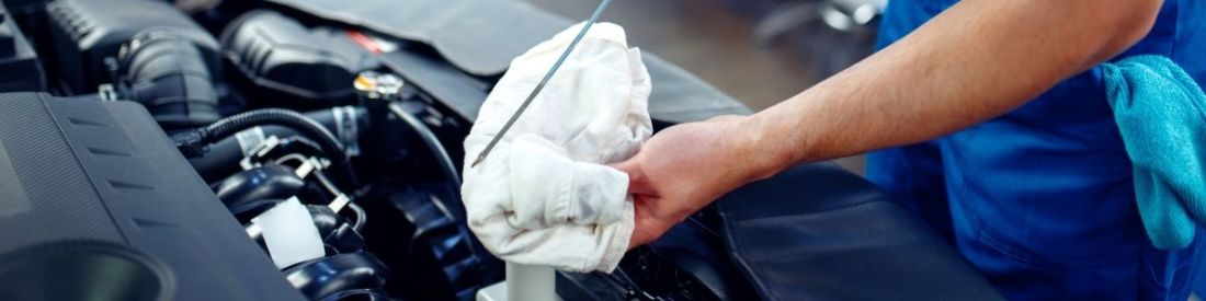 A car bonnet lifted and a mechanic checking the dipstick