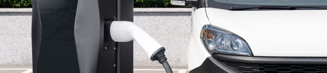An electric van connected to a charging point.
