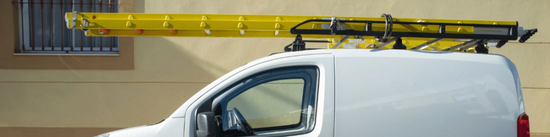 A yellow ladder on top of a small white van