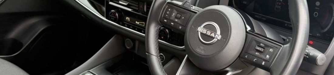 Nissan steering wheel and modern car interior with multifunction controls.