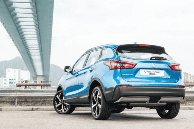 Blue Nissan Qashqai parked beneath a bridge in an urban setting.