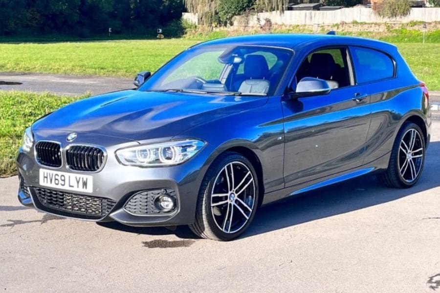 Grey BMW 1 Series parked in front of grass.