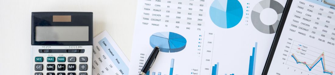 Financial documents with charts and graphs alongside a calculator and pen on a desk.