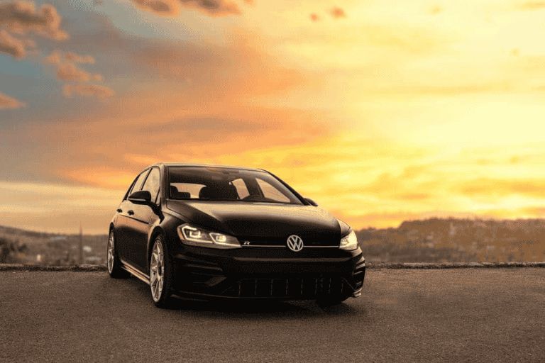 Black Volkswagen Golf parked on an open road at sunset.