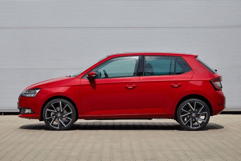 Red Škoda Fabia hatchback parked against a grey studio backdrop.