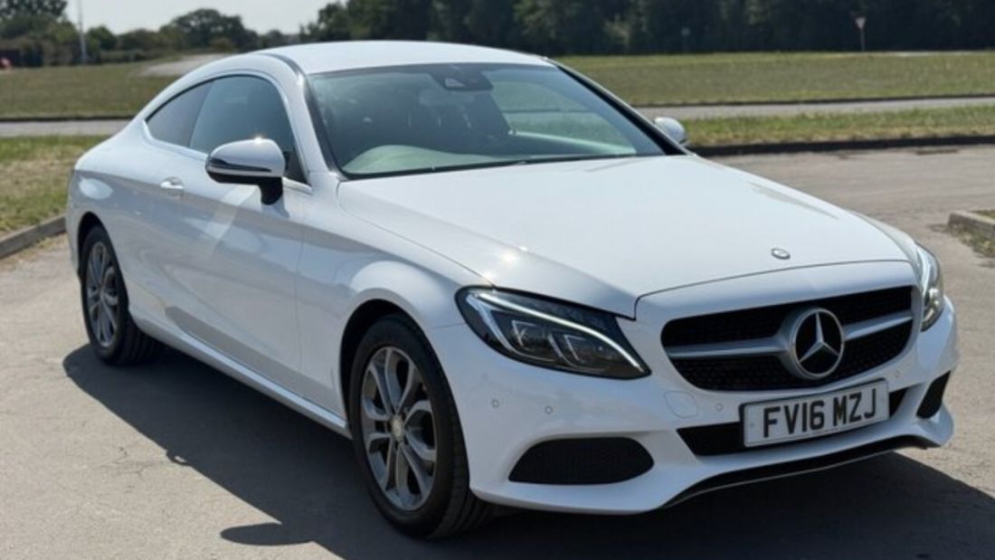 White Mercedes-Benz coupe parked outdoors in front three quarter view.