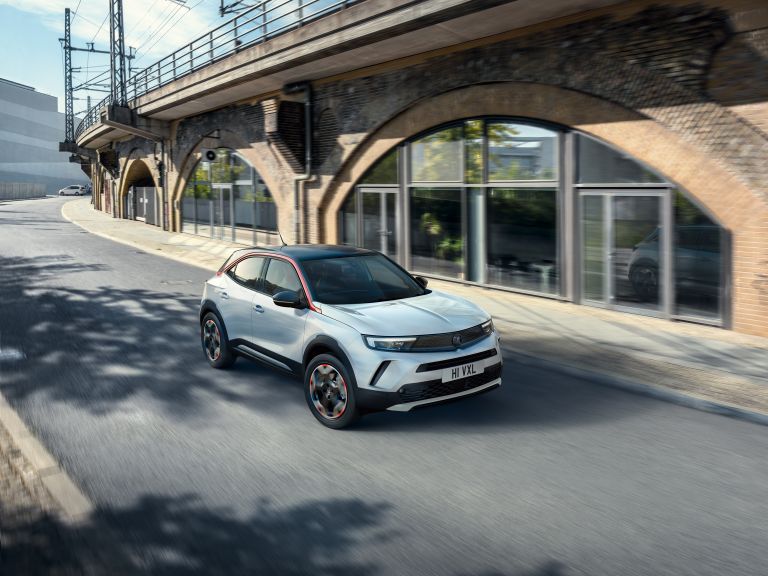 White Vauxhall Mokka driving through an urban street beneath railway arches.