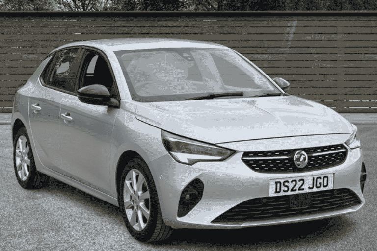 Silver Vauxhall Corsa in front of a wooden gate.