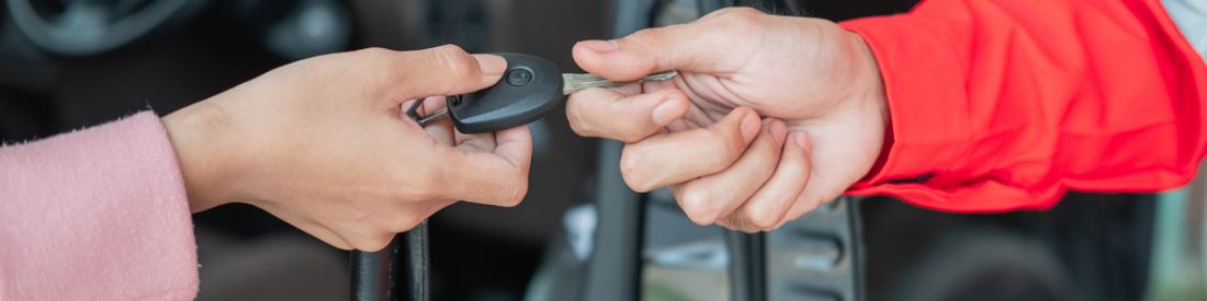 Close-up of two people exchanging car keys, symbolising buying or selling a car.
