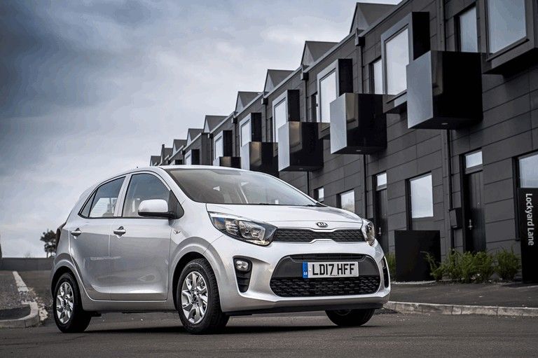 Silver Kia Picanto parked outside modern townhouses.