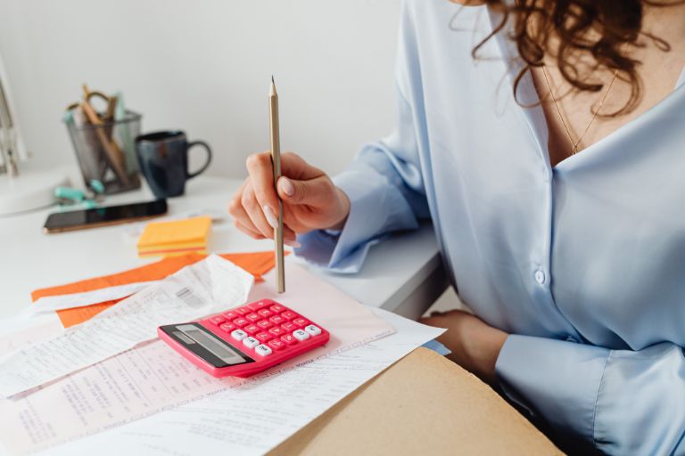 A woman with paperwork and a calculator on her desk, working out how to improve her credit score.