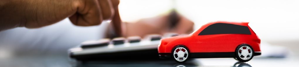 Car finance concept with red model car and calculator on office desk.