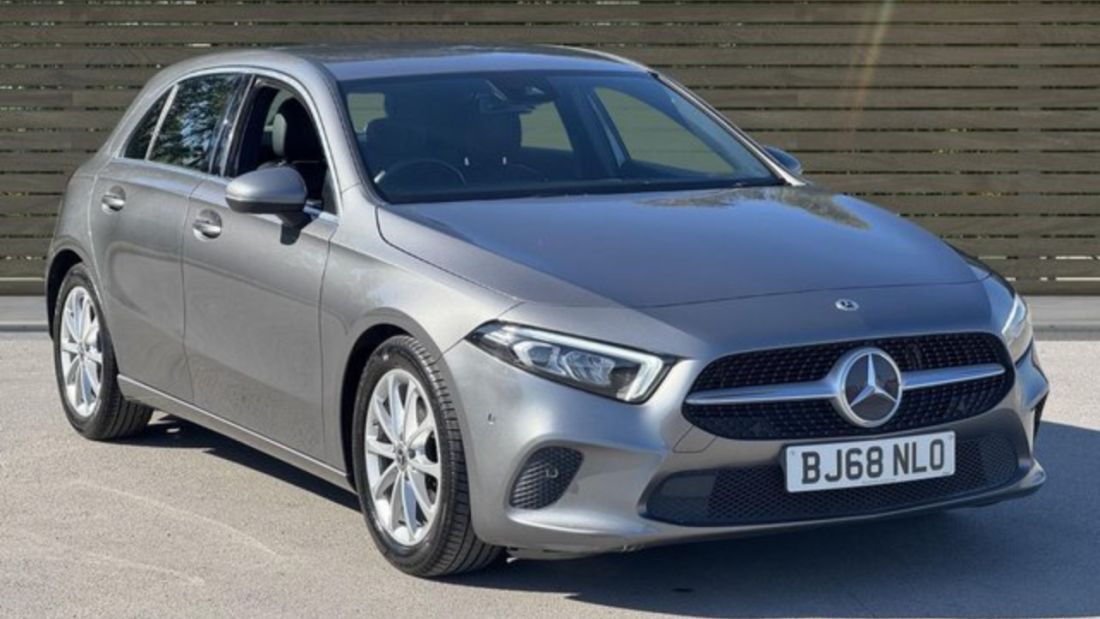 Front and side view of a grey Mercedes-Benz hatchback, parked outdoors.