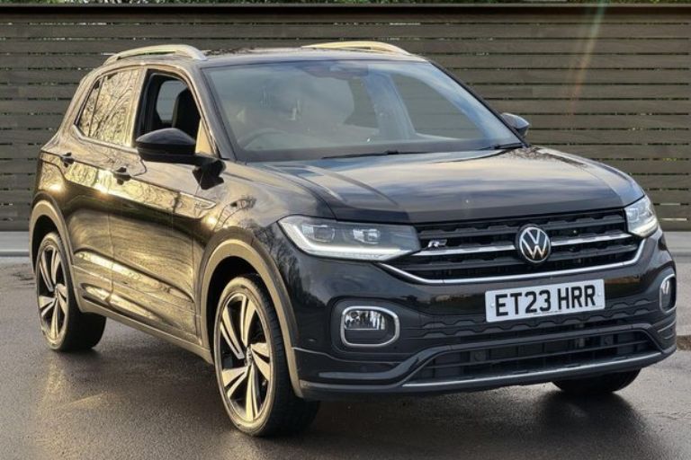 A black Volkswagen T-Cross parked outdoors at a used car dealership.