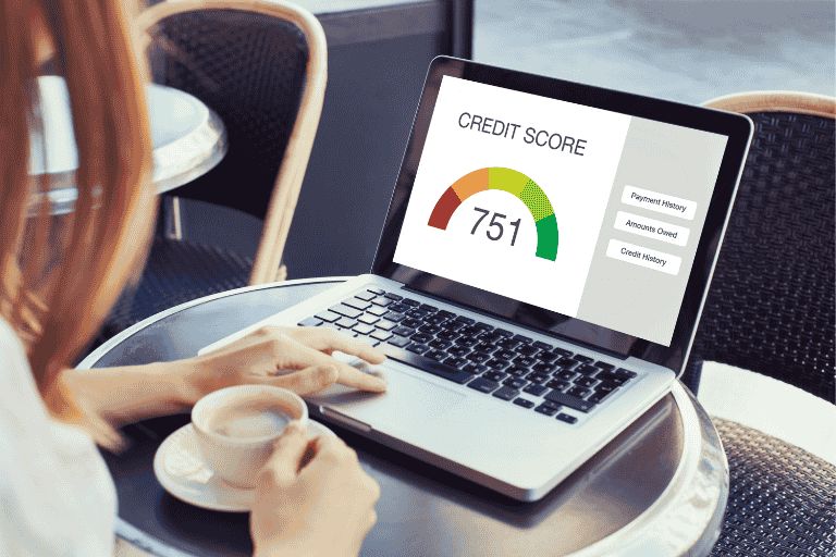 Someone checking their credit score on a laptop whilst drinking a coffee.