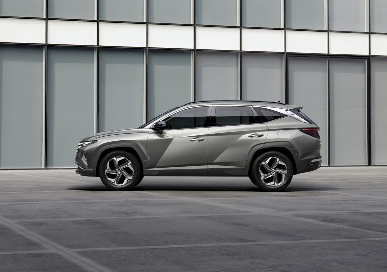 Grey Hyundai Tucson SUV parked outside a modern glass building.