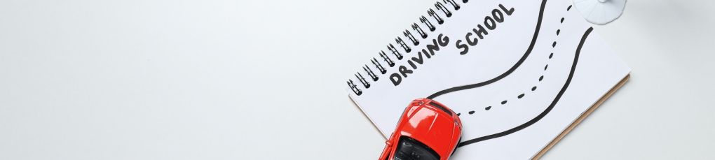 Driving school notebook with toy car and learner driver route illustration.