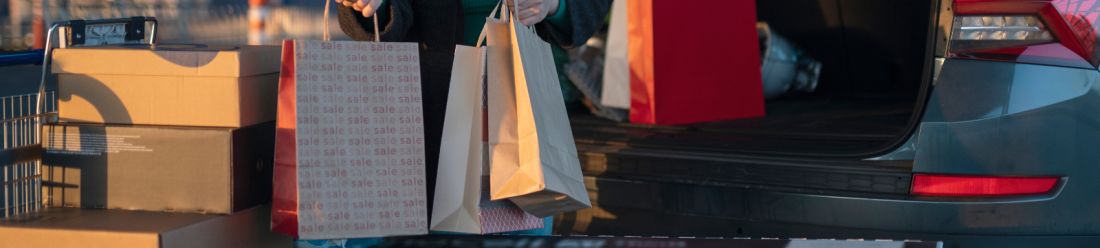 Open car boot filled with shopping bags and boxed purchases outdoors.