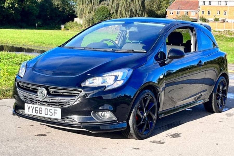 Black Vauxhall Corsa, parked in front of grass.