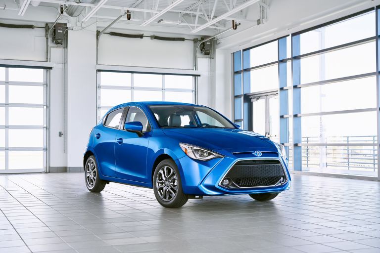 Blue Toyota Yaris hatchback parked inside a modern showroom.