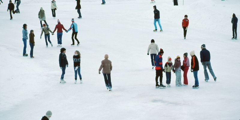 People ice skating on an outdoor ice rink during winter.