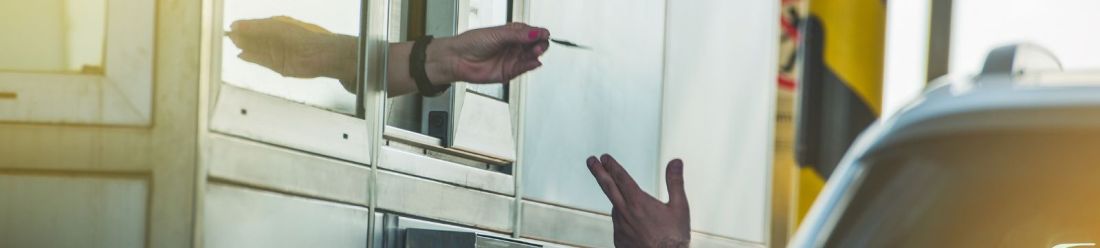 Customer receiving car park or drive through ticket from payment booth window.
